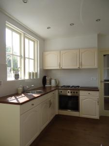 a kitchen with white cabinets and a sink and a stove at t Laege Uus in Burgh Haamstede