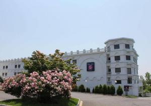 a white building with a flowering tree in front of it at Raritan Hotel in Edison