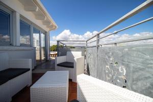 Un balcón con sillas blancas y vistas al océano. en Bianca Dimora en Torre Canne