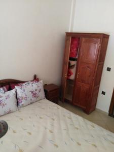 a bedroom with a bed and a wooden cabinet at Al Oualidia Dar Diafa in Oualidia