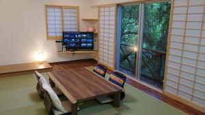 a room with a table and chairs and a large window at Big Tree JUDO ハウス in Urasoe