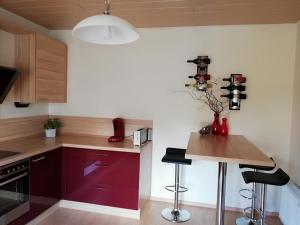 a kitchen with red cabinets and a wooden table at Ferienwohnung am Töpferplatz in Höhr-Grenzhausen +11 photos