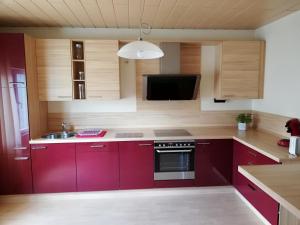 a kitchen with red cabinets and a sink and a tv at Ferienwohnung am Töpferplatz in Höhr-Grenzhausen