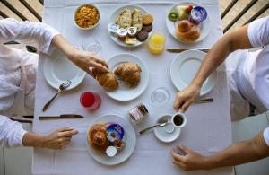 un grupo de personas sentadas en una mesa con comida en Hotel Za Maria, en Santo Stefano di Camastra