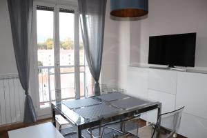 ein Wohnzimmer mit einem Glastisch und einem TV in der Unterkunft IR Panoramic in Triest