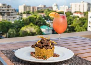 einen Teller mit Essen und einen Drink auf dem Tisch in der Unterkunft Ciqala Luxury Suites - San Juan in San Juan