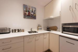 a white kitchen with a sink and a microwave at The Sails in Russell