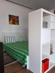 1 dormitorio con cama verde y estanterías blancas en Cozy Place, en Sintra