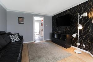 a living room with a couch and a flat screen tv at Lomond Serviced Apartments- Muir House in Motherwell