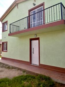 a green house with a white door and a balcony at Casa en Mina Clavero in Mina Clavero +7 photos