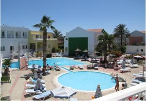 a large swimming pool with people sitting around it at Valsami Hotel Apartments in Kremasti