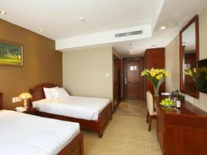 Habitación de hotel con 2 camas y escritorio en Dong Ha Fortuneland Hotel, en Can Tho