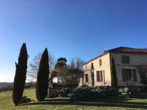 an old stone house with cypress trees in a field at Agape Du Gers in Montréal