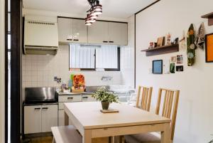 eine kleine Küche mit einem Holztisch und Stühlen in der Unterkunft Kashikiri Ikkenya Sora in Osaka