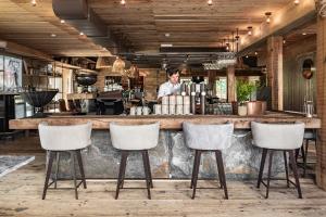 Człowiek stojący za barem z czterema stołkami. w obiekcie HOTEL SEPP - Alpine Boutique Hotel - Adults Only ab 21 Jahre w mieście Maria Alm am Steinernen Meer