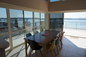 a dining room with a table and chairs and a large window at Moorings Beach Resort in Caloundra
