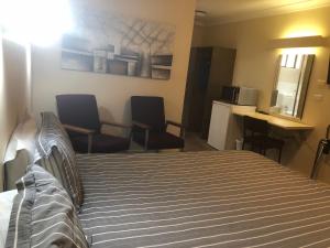 a hotel room with a bed and two chairs at Anna Bella Motel Glen Innes in Glen Innes