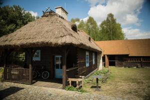 Cabaña pequeña con techo de paja y banco en Zagrodowa Osada, en Kazimierz Dolny