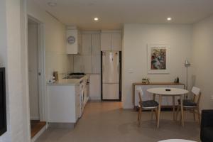 a kitchen with a table and a white refrigerator at Point Lonsdale 1 Bedroom Apartment in Point Lonsdale
