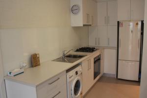 a white kitchen with a sink and a refrigerator at Point Lonsdale 1 Bedroom Apartment in Point Lonsdale