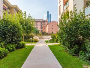 a walkway through a park with buildings and trees at easyhomes-Timavo in Milan