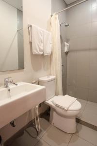 La salle de bains est pourvue d'un lavabo, de toilettes et d'un miroir. dans l'établissement LeGreen Suite Kuningan, à Jakarta