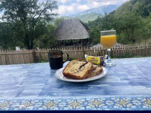 a table with a plate of bread and a glass of orange juice at Casa Albastră in Băile Olăneşti