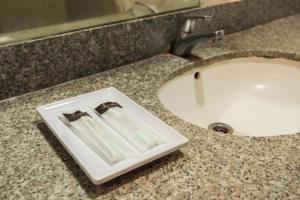 a bathroom sink with a toothbrush holder next to a sink at LeGreen Suite Pejompongan in Jakarta