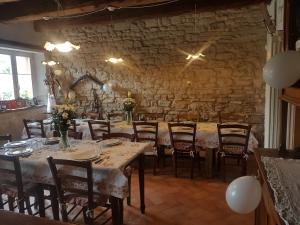comedor con mesas y sillas y pared de piedra en Agriturismo Piccola Raieda en Sasso Marconi