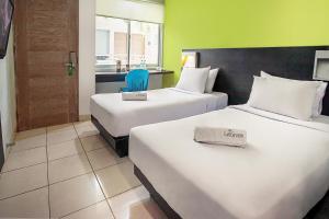 una habitación de hotel con 2 camas y una silla azul en LeGreen Suite Pejompongan, en Yakarta
