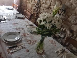 una mesa con un jarrón de flores blancas. en Agriturismo Piccola Raieda, en Sasso Marconi