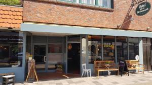 un magasin à l'avant d'un bâtiment en briques avec des tables et des bancs dans l'établissement Frühstückshotel Fürstenwerth, à Wilhelmshaven