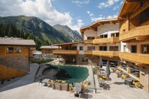 a resort with a pool and mountains in the background at das Chaletdorf - Pitztal in Sankt Leonhard im Pitztal