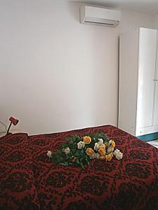 Una cama con una manta roja con flores. en Jolly en Bibione