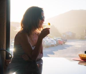 a woman sitting at a table holding a drink at Pili Pili Beach Cabanas in Sedgefield