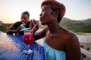a woman sitting at a table drinking a drink at Pili Pili Beach Cabanas in Sedgefield