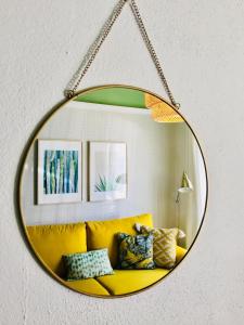 a mirror hanging on a wall with a yellow couch at SanJose27 in Palos de la Frontera
