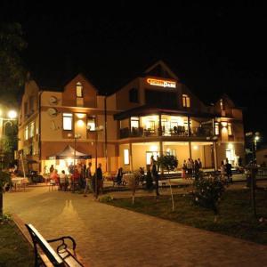 a building with people sitting outside of it at night at Hotel Central Park in Velyikyy Bychkiv