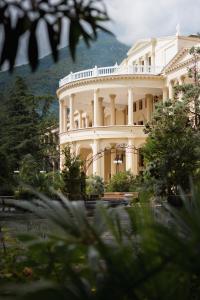 a large white building with trees in front of it at Amra Park-hotel & Spa in Gagra