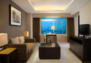 a living room with a couch and a tv at Hotel Santika Premiere Slipi Jakarta in Jakarta