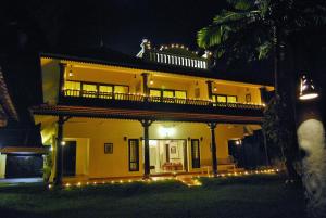 een groot geel huis met een balkon in de nacht bij Wintergreen Water Front Resort in Tripunittura