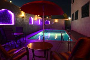 a swimming pool with a table and an umbrella at Larsa Hotel in Amman