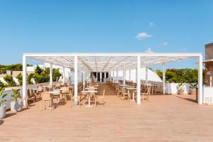 a pavilion with tables and chairs on a boardwalk at Torre Cintola Greenblu Sea Emotions in Monopoli