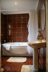 
a bath tub sitting next to a sink in a bathroom at Hanora's Cottage Guesthouse and Restaurant in Ballymacarbry
