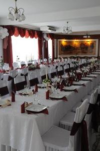 une grande salle de banquet avec des tables et des chaises blanches dans l'établissement Hotel Kaukaska, à Wolsztyn