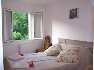 a bedroom with a bed with a window and a chair at Aux 4 Saisons in Tabre