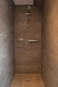 La salle de bains est pourvue d'une douche avec du carrelage brun. dans l'établissement Boardinghouse Sorgenfrei, à Hagen