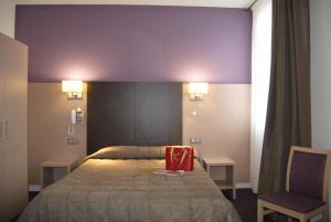 a hotel room with a bed and a chair at Hôtel Roc de Massabielle in Lourdes