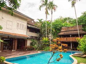 a villa with a swimming pool in front of a house at Baan Orapin in Chiang Mai