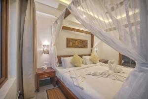 Elixir Hills Suites Resort and Spa في مونار: غرفة نوم بسرير أبيض مع مظلة